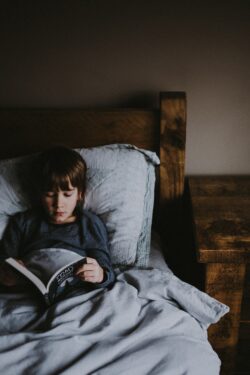 Child reading a book in bed