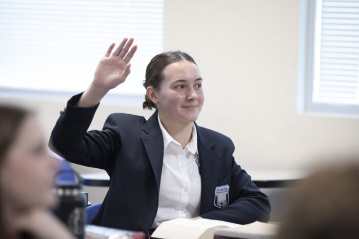Scholar raising her hand in class.