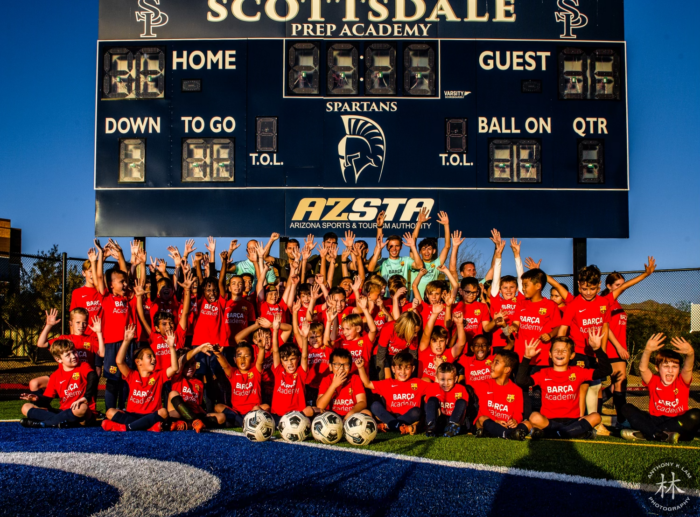 2023 Barca Soccer Camp group photo in front of scoreboard