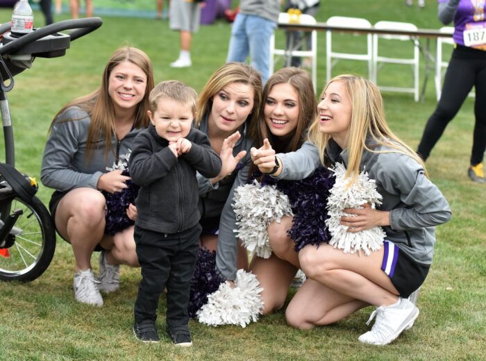 Becky Heller, former GCU Cheerleader with teammates posing with a child