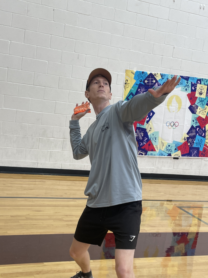 Staff member participating in shot put competition at the Trivium Prep Staff Olympic Games