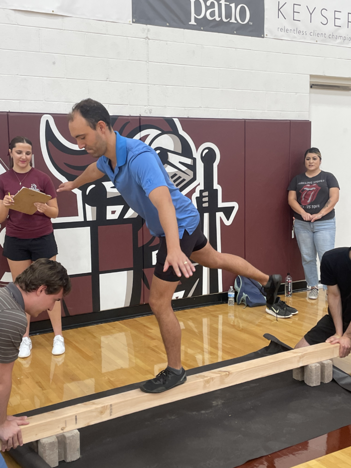 Staff member participating in balance beam competition at the Trivium Prep Staff Olympic Games