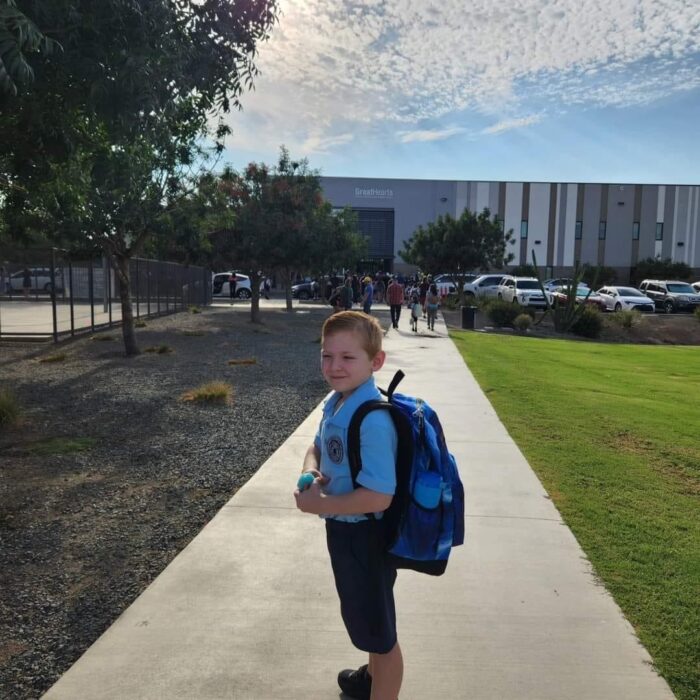 A student in front of a Great Hearts school on first day