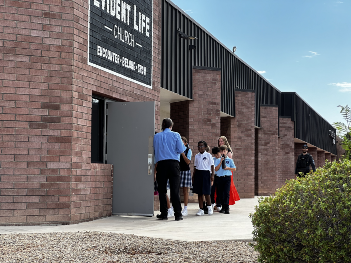 Teacher holding door open for students at entrance of Great Hearts Christos in Gilbert