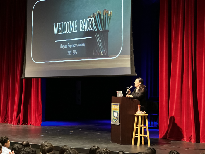 Headmaster Mercado at podium with a "Welcome Back" slide at a new school year orientation