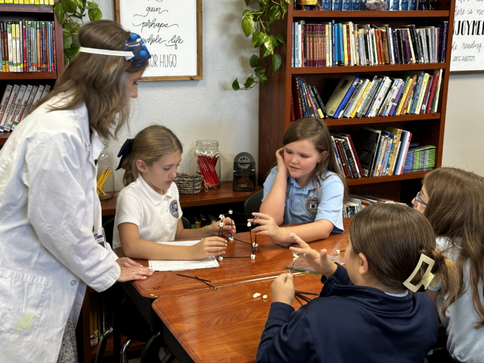 Students working on a science project with teacher looking on