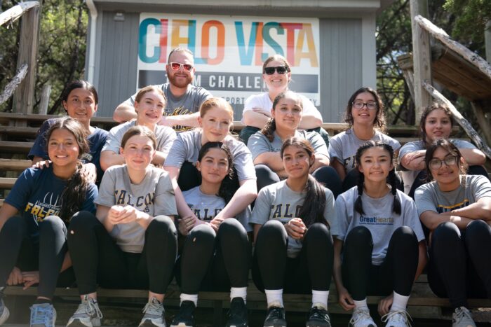 Group of students and coaches sitting in front of a "Cielo Vista" sign