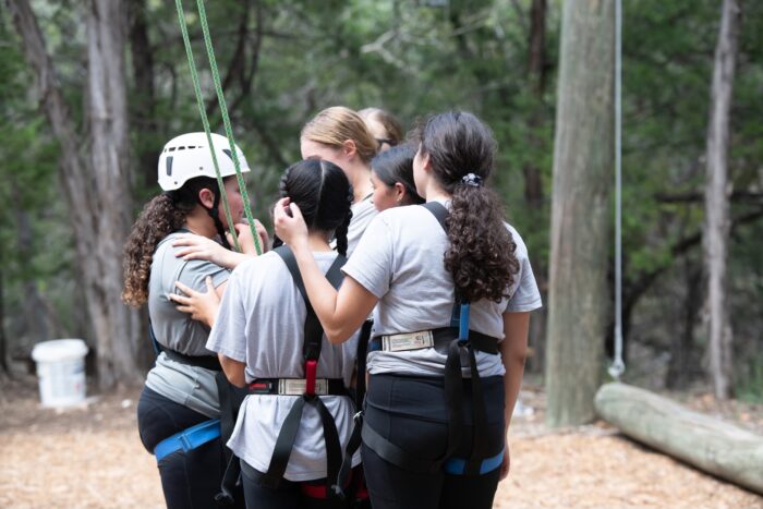 group of students with harnesses getting ready for rope challenge