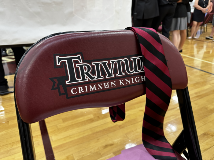 Folding chair with Trivium logo and striped tie laying across the seat back.