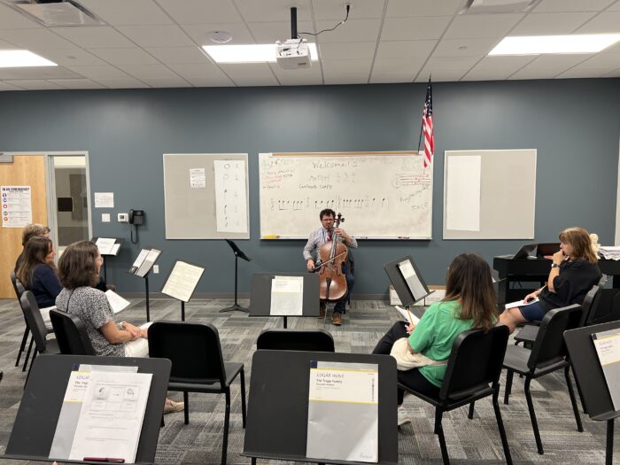 Music teacher playing instrument for parents