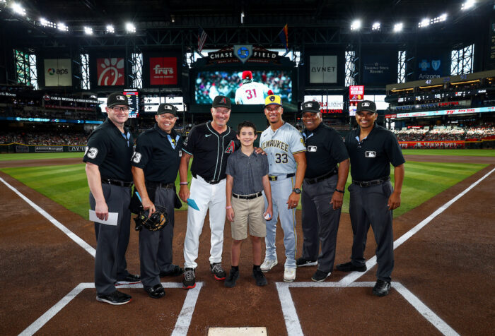 Great Hearts student at home plate with coaches and umpires