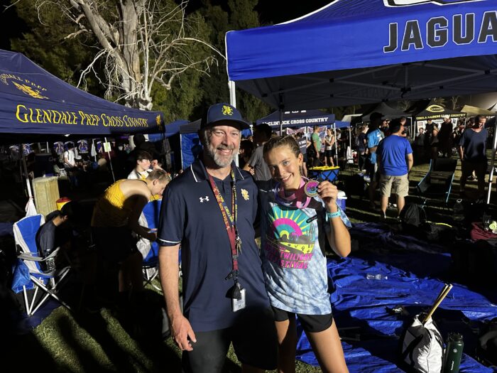 Track coach with a student runner holding a medal