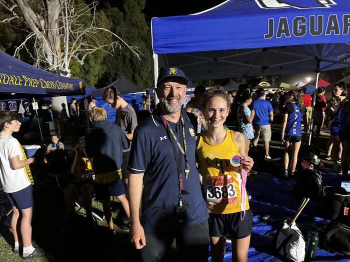 Track coach with a student runner holding a medal