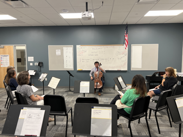 Dr. Duarte playing cello in front of a classroom