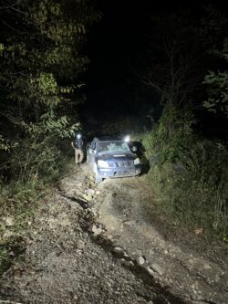 Off road vehicle and 2 first responders on a washed out road