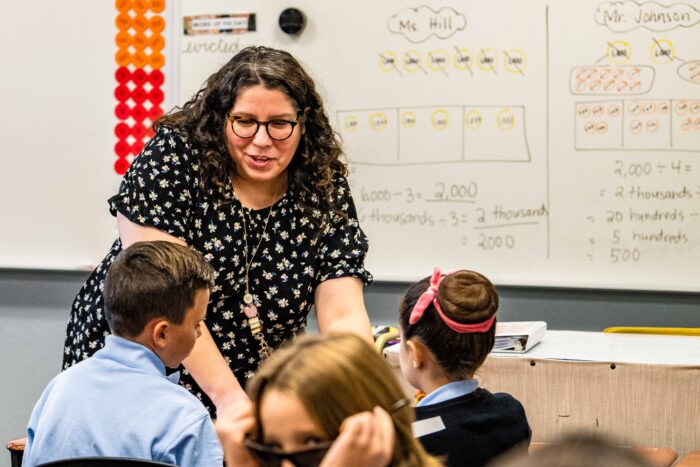 Ms. Trujillo working with two students at their desks