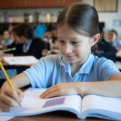 Female student writing in a workbook at her desk