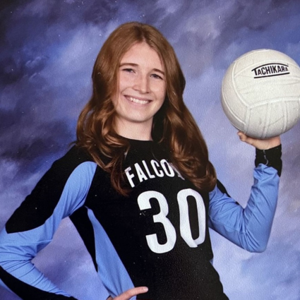 Female student in volleyball jersey holding a volleyball