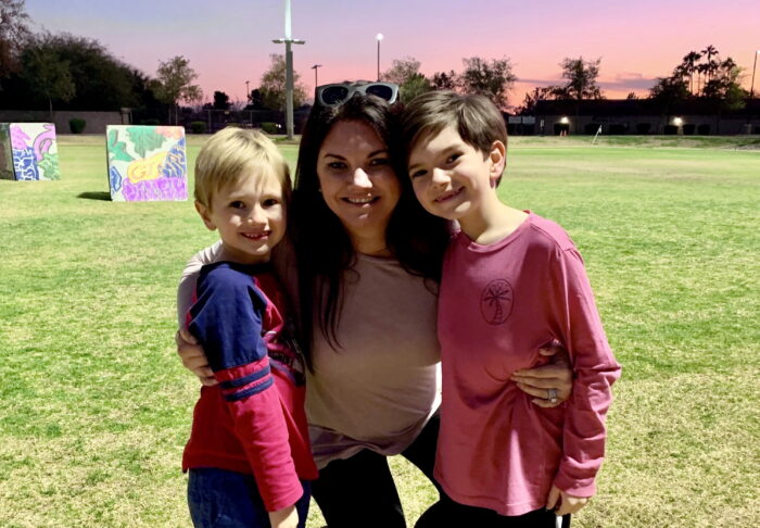 A mother with her two children on a school field at dusk