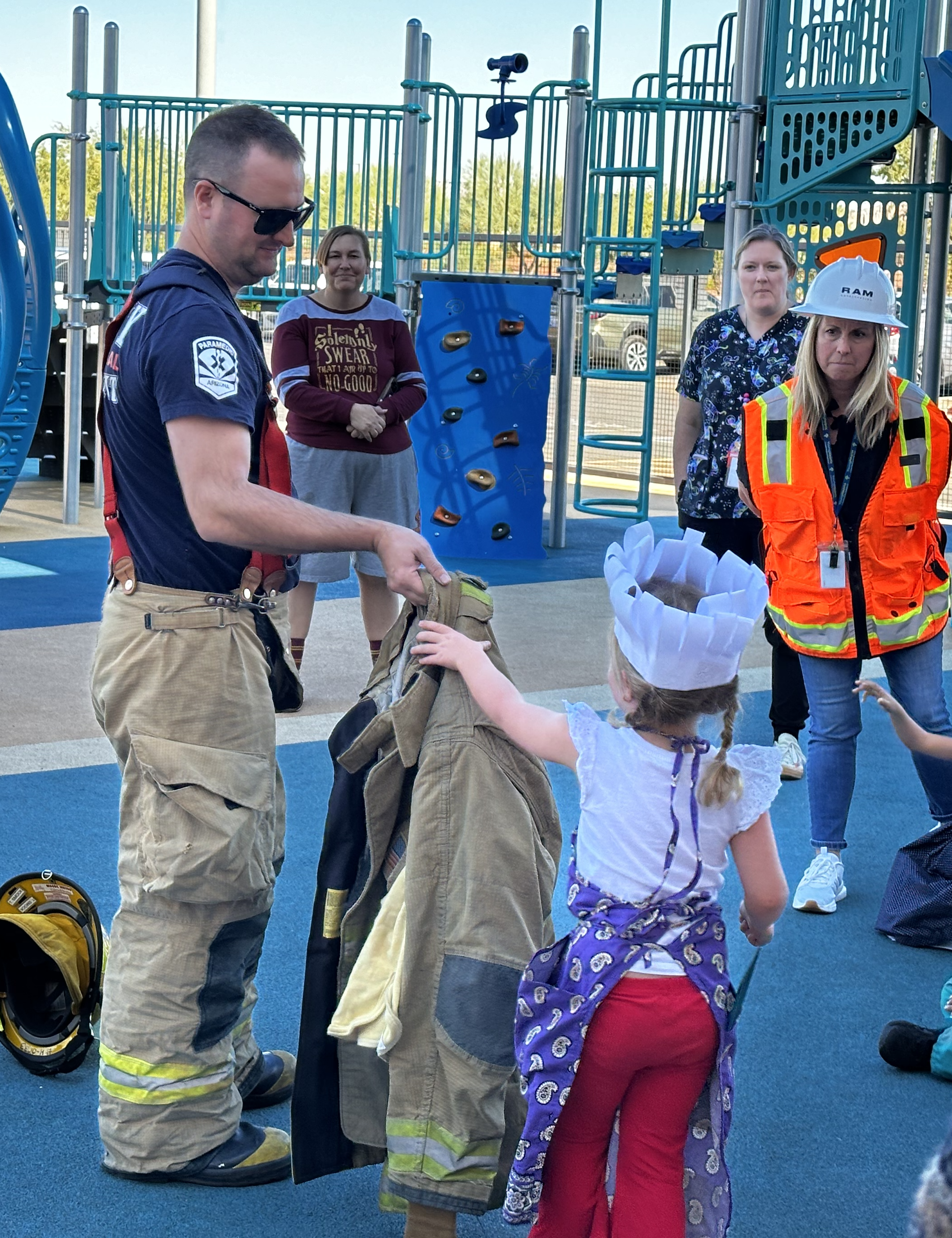 Firefighter showing gear to a preschooler