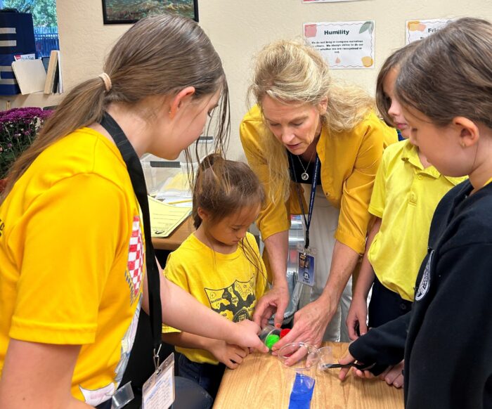 Group of students with teacher, all dressed in yellow, working on a project