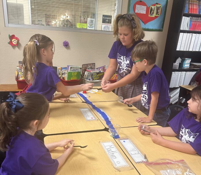 Students all wearing purple, working on a project