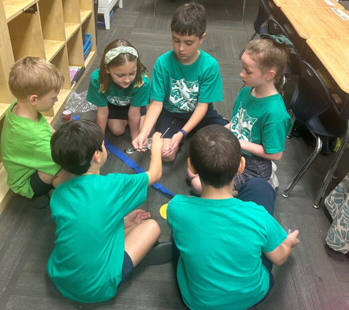 Students wearing green, working on a project together