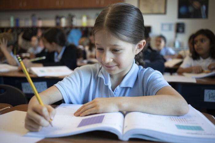 Female student writing in a workbook at her desk