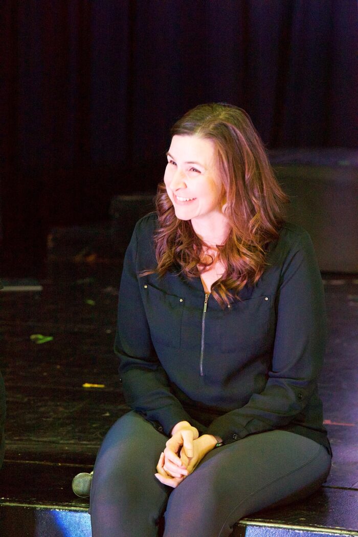 Mrs. MacLeod sitting on a stage laughing