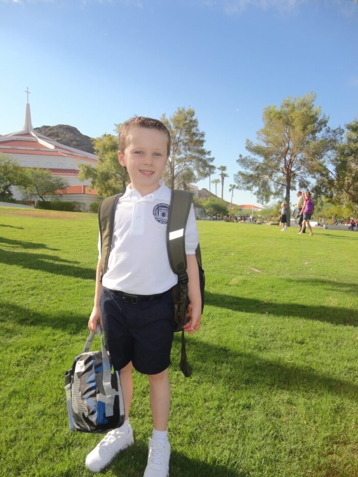 Young male archway student with a backpack and lunch bag