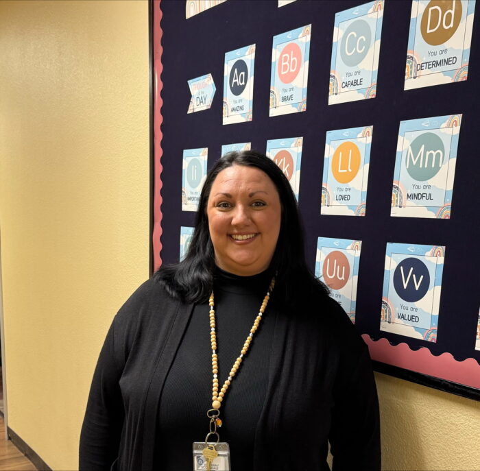 Mrs. Gonzalez in front of a bulletin board