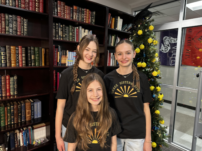 Three girls with "Three Sisters Give" shirts