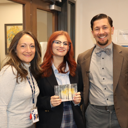 Student posing with Headmaster and art teacher with her artwork