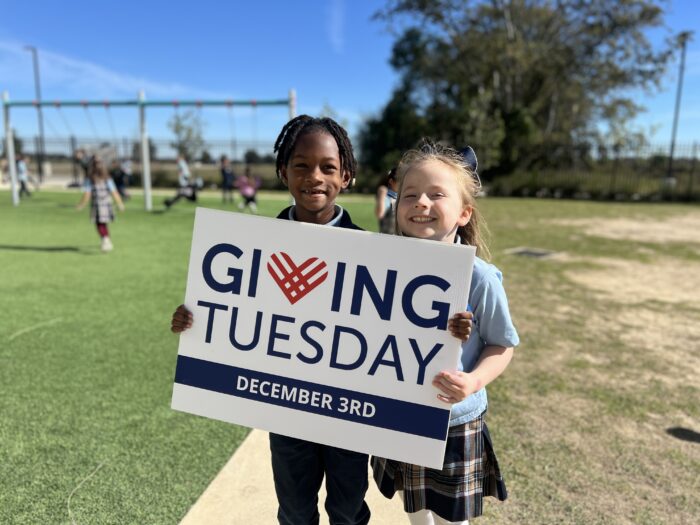 Two young girls holding a "Giving Tuesday" sign