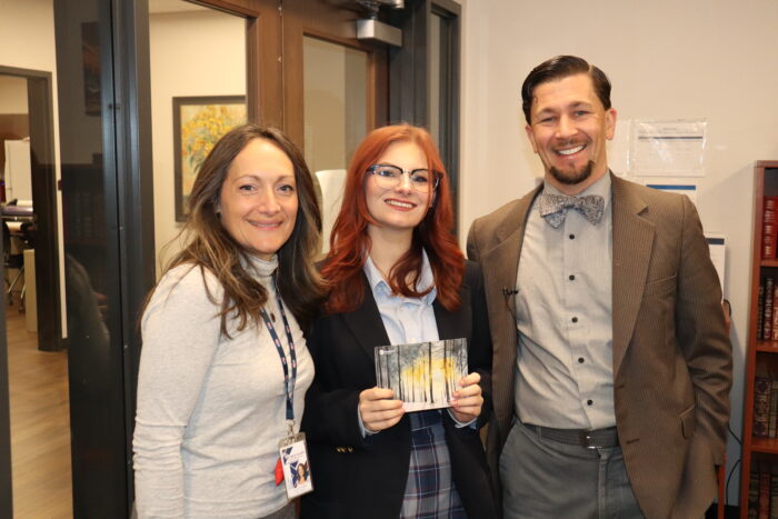 Student posing with Headmaster and art teacher with her artwork