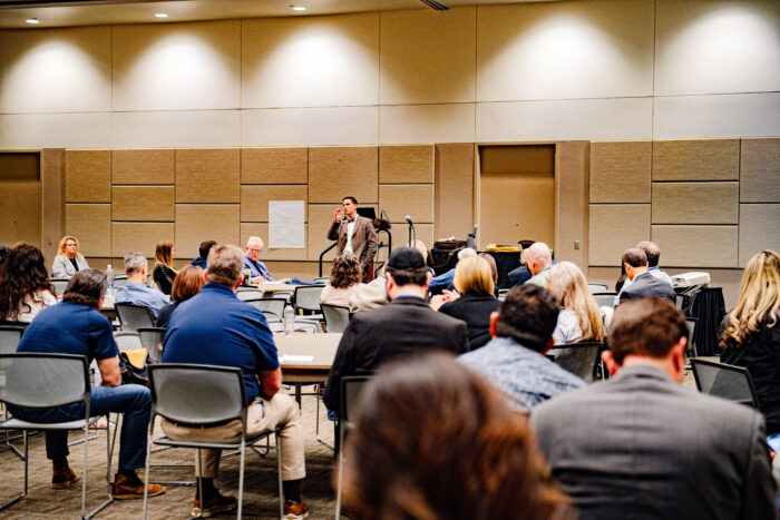 Attendees at a workshop listening to a speaker in the front of the room.