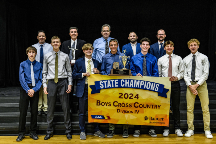 The boys cross country team holding their 2024 Division IV State Champions banner