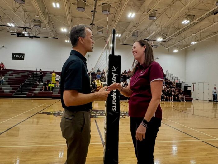 Coach Beth Wilson receiving award on volleyball court sidelines