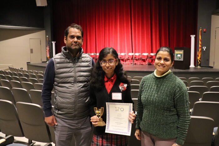 2025 Spelling Bee winner holding trophy and certificate with her parents