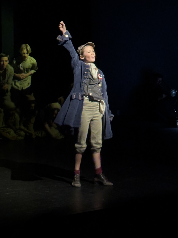 Actress from Les Miserables with hand raised