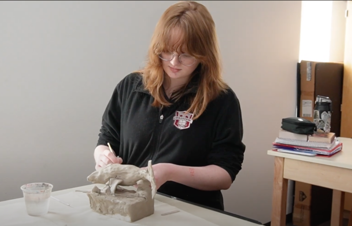 student sculpting a clay shark.