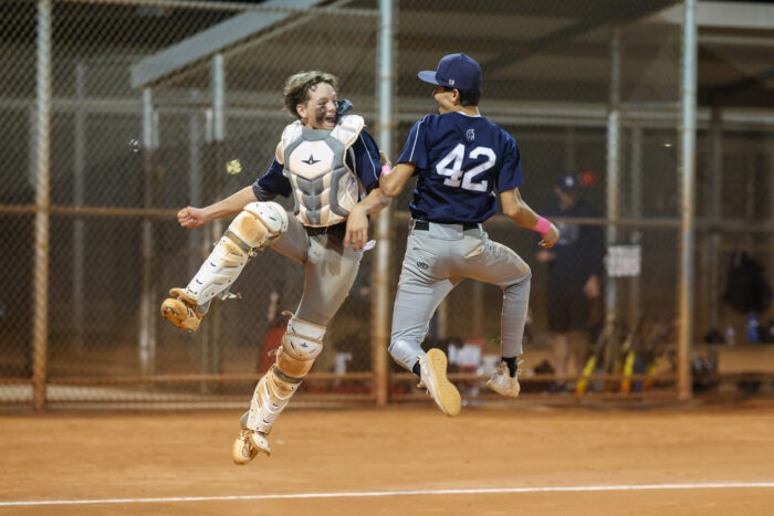 Two Middle School baseball players jumping in mid air