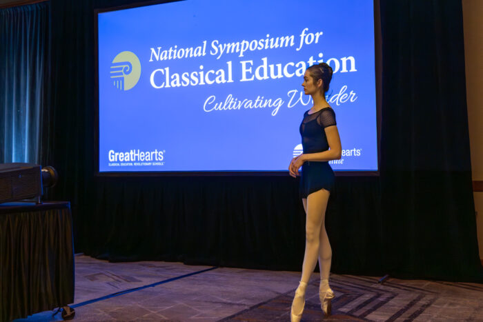 Ballet dancer in front of screen that says, "National Symposium for Classical Education Cultivating Wonder."