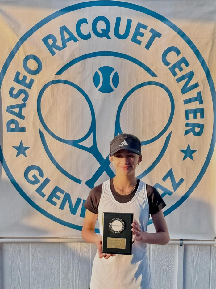 Middle School tennis player holding a tennis trophy in front of Paseo Racquet Center sign