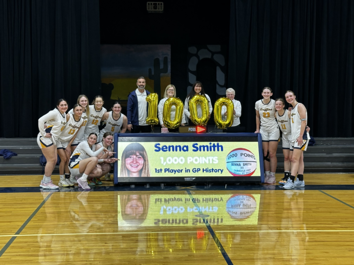 Basketball team and coaches posing with "1,000" in balloons and digital banner reading, "Senna Smith 1,000 points"