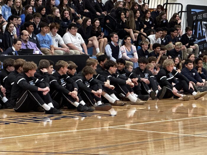 basketball players sitting court side at a pep assembly