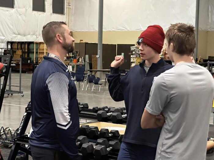 Students talking to instructor about weight lifting techniques