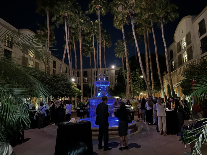 A courtyard with a fountain palm trees at night