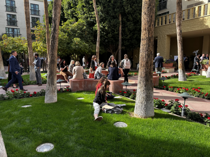 Symposium attendees in a sunlit courtyard.