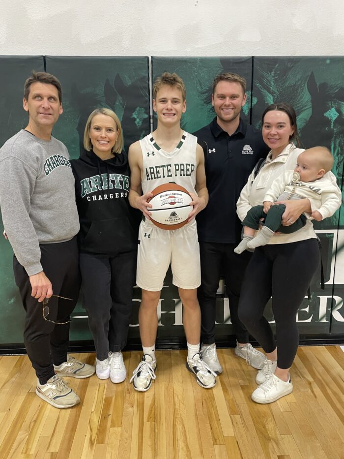 Arete athlete holding a basketball and posing with his family